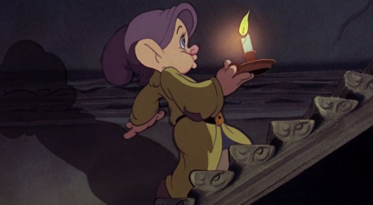 Dopey quietly walking up stairs with a candle